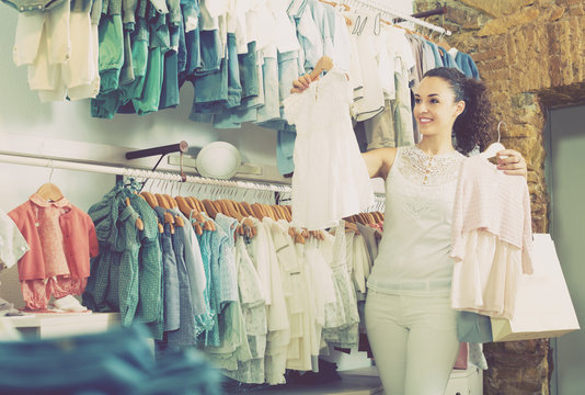 Cheerful female customer choosing baby dress