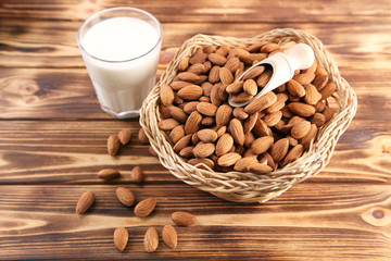 Almonds in basket with glass of milk on brown wooden table
