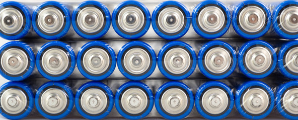 Lots of blue batteries, type AA, Packed in polyethylene film, on a white background, macro
