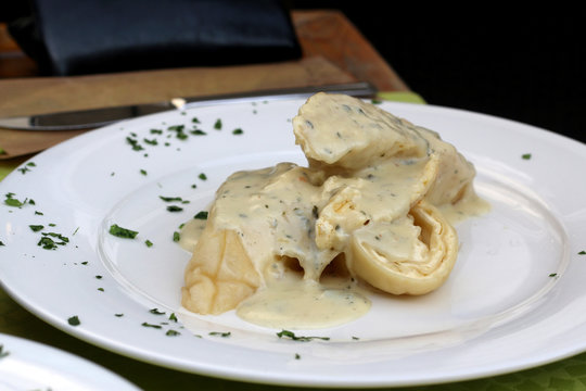 Traditional Slovenian meal called 'Strukelj' - rolled dumpling filled with cheese and creamy Gorgonzola cheese sauce. Selective focus. 