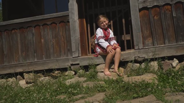 little girl is sitting on the porch of the house