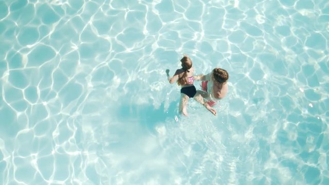 High-angle shot of a father teaching daughter to swim