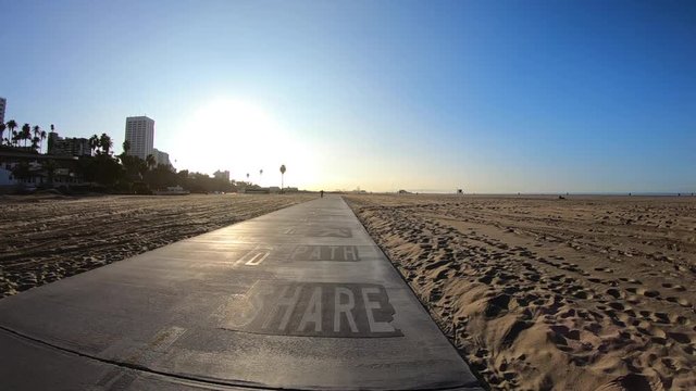 Los Angeles beach bike path with slow motion movement towards morning sun.