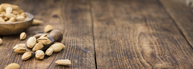 Roasted Almonds (in shell) on a wooden table (selective focus)