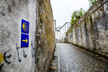 Yellow scallop shell and arrow on a wall signing the way to santiago de compostela in Galicia. Most...