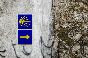 Yellow scallop shell and arrow on a wall signing the way to santiago de compostela in Galicia. Most...
