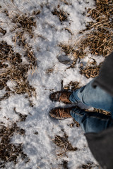 Male legs in blue jeans and winter shoes on snow, close-up.