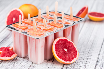Old wooden table with freshly made Grapefruit Popsicles
