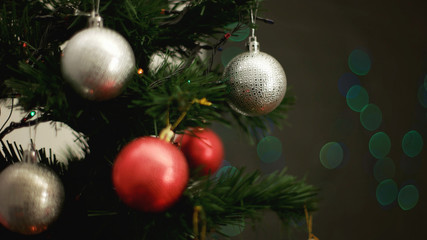 Christmas tree with red and silver toys on light bokeh background. Close up.