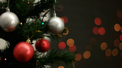 Christmas tree with red and silver toys on light bokeh background. Close up.