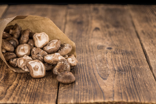 Portion of Raw Shiitake mushrooms on wooden background, selective focus