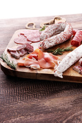 Wooden cutting board with prosciutto, salami, sausages  and  rosemary