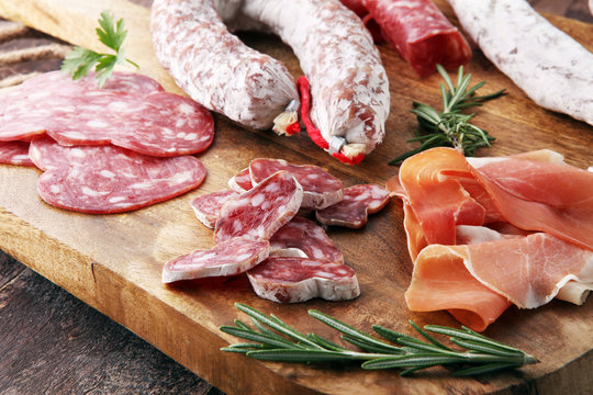 Wooden cutting board with prosciutto, salami, sausages  and  rosemary