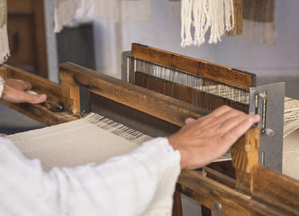 Hands of a man weaving on a loom