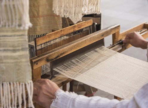 Hands of a man weaving on a loom
