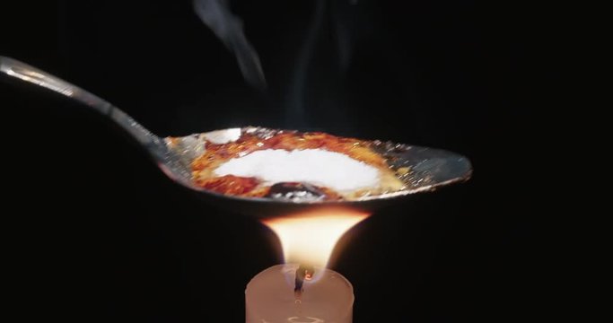Cooking Heroin on Spoon Close Up on Candle. a close up view of a spoon cooking heroin