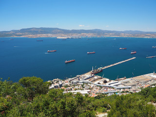 Container and cargo ships around the Rock of Gibraltar with the port of Algeciras, Spain, in the...