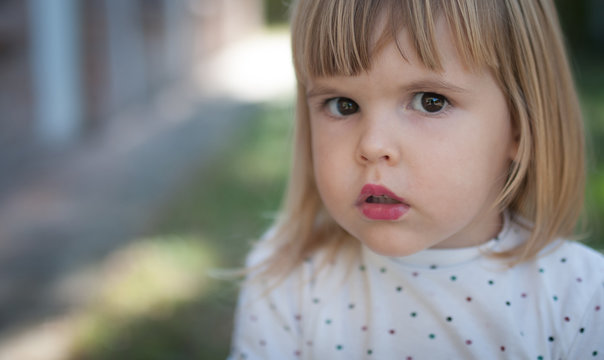 Closeup portrait of confused little girl wizh lipstick