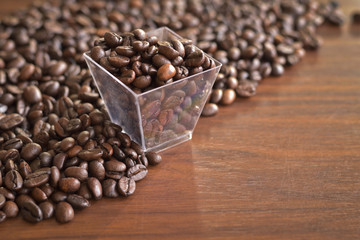 roasted coffee beans in an old plastic box and heap of coffee put on wooden table. Top view and copy space.