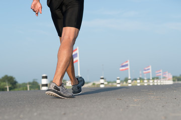 Down view of a man asia legs running in the time during sunrise on dam road exercise.Healthy lifestyle