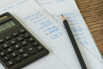 Financial office salary man or tax calculation concept as black calculator and pencil on salary slips with numbers