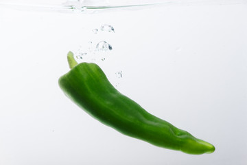 One jalapeno peppers on white background in water with bubbles.