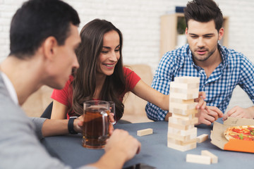The company of young people plays a table game called jenga.
