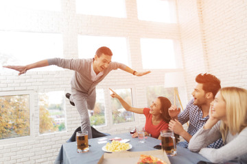 The company of young people play the game with stickers on the forehead.