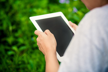 Hands using tablet computer in green field