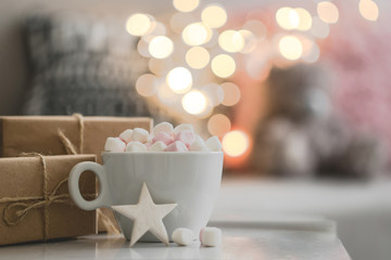 Cup of hot chocolate and marshmallow in the background of Christmas decorations.