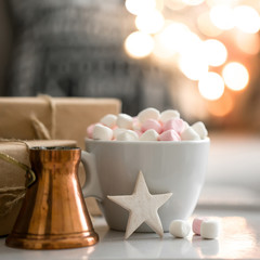 Cup of hot chocolate and marshmallow in the background of Christmas decorations.