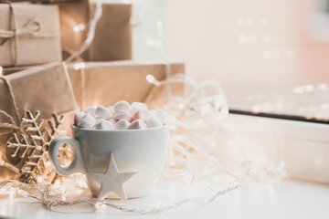 Cup of hot chocolate and marshmallow in the background of Christmas decorations.
