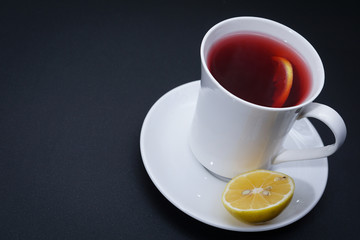 Red tea in white cup with lemon slice  on dark background