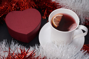 Cup of red tea with lemon slice, present on dark table