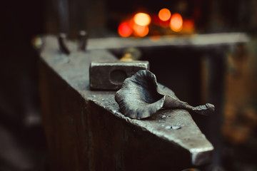 A metal forged rose lies on the pier in the smithy