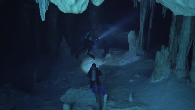 cenote with beautiful blue water, divers swiming through stalagmit cave, cenote dos ojos