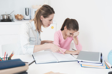 Mom helps my daughter do her homework in the kitchen.