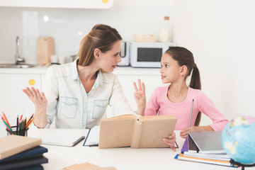 Mom helps my daughter do her homework in the kitchen.