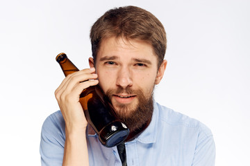 Naklejka premium Young guy with a beard on a white isolated background holds a bottle of beer