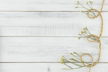 Brown rope decorate with yellow limonium caspia flowers on white wood background with copy space