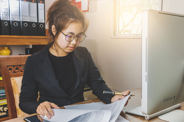 Businesswoman wearing glasses reading and checking sheets on her office. business working concept