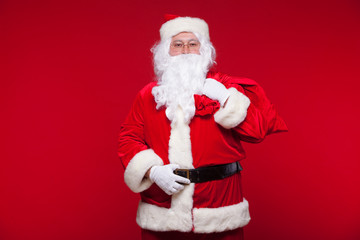 Fototapeta na wymiar Christmas. santa claus with big bag on shoulder is on red background