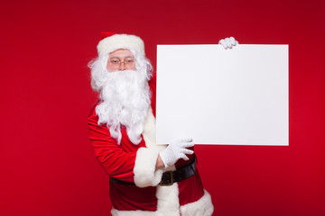 Santa Claus pointing in blank advertisement banner isolated on red background with copy space