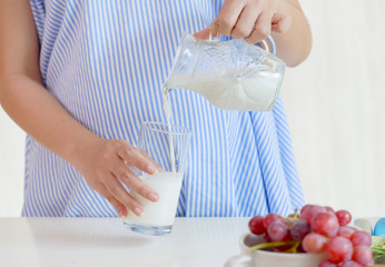Obraz na płótnie Canvas Young pregnant woman pouring milk ,healthy nutrition during pregnancy