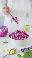 Obraz na płótnie Canvas Salad of red cabbage and corn. Woman's hand holds fork with salad