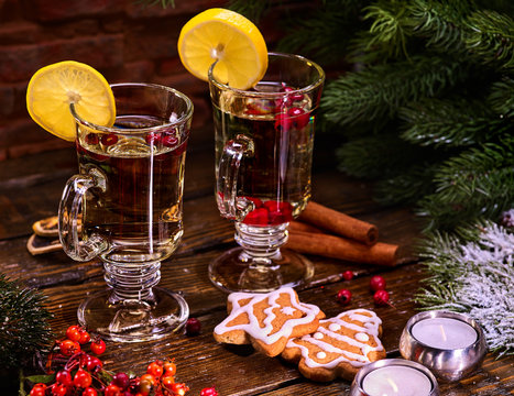 Christmas gingerbread with pair mug decoration lemon slice hot drink on wooden table. Xmas cookies on plate with cinnamon sticks. White hot wine and berry under fir branches.