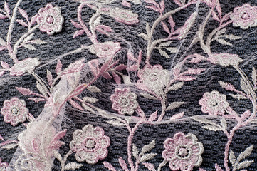 Texture, background, pattern. Pink lace decorated with flowers on a black background. Lace...