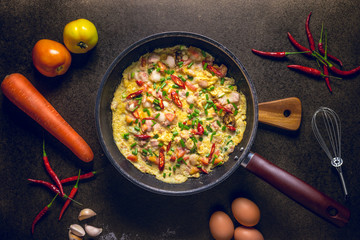 Omelette in frying pan on dark background, top view. garlic and fresh tomatoes. Traditional