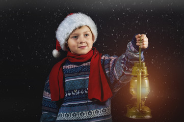 Obraz na płótnie Canvas Boy in Christmas hat with a lantern in his hand, merry Christmas