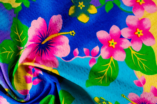 Texture, pattern. Cloth with patterned patterns of bright colors on a blue yellow background. Bright Batika fabric with a blue background and multi-colored flowers.